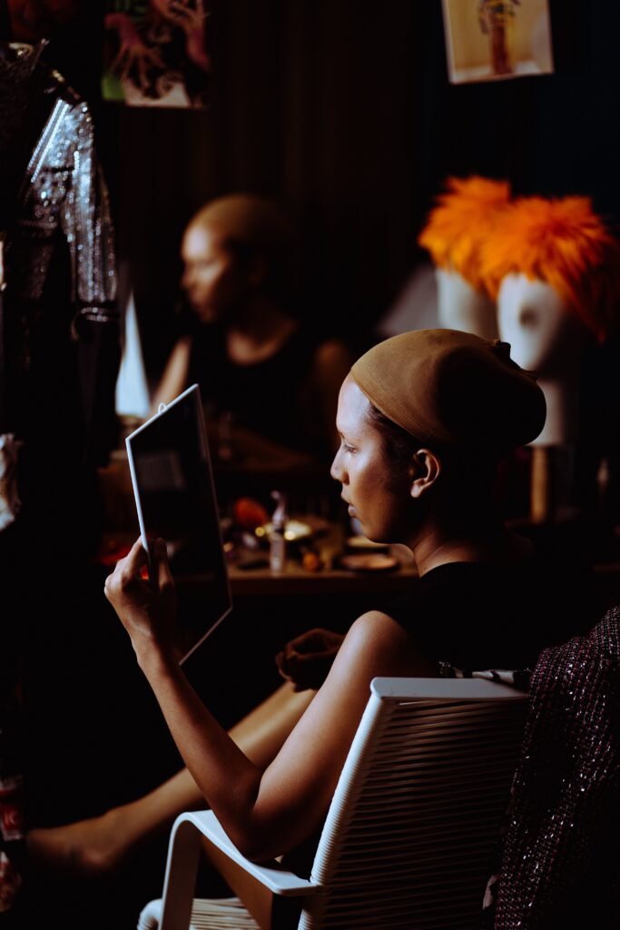 Side view of ethnic female admiring stylish makeup in mirror in dressing room